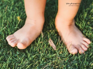 پاهای کودک روی چمن سبز نشان دهنده رشد طبیعی پا